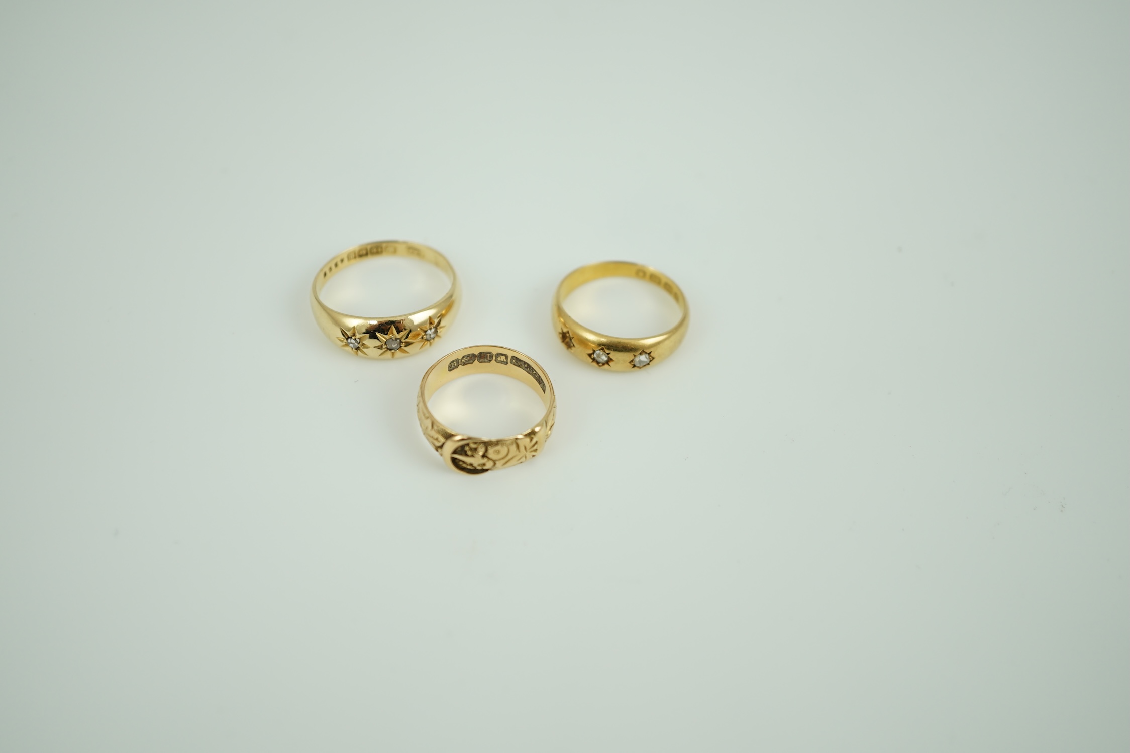 A Victorian 18ct gold buckle ring, size K/L, a Victorian 18ct gold and gypsy set three stone diamond ring (stone missing) and a later 18ct gold and gypsy set three stone diamond ring